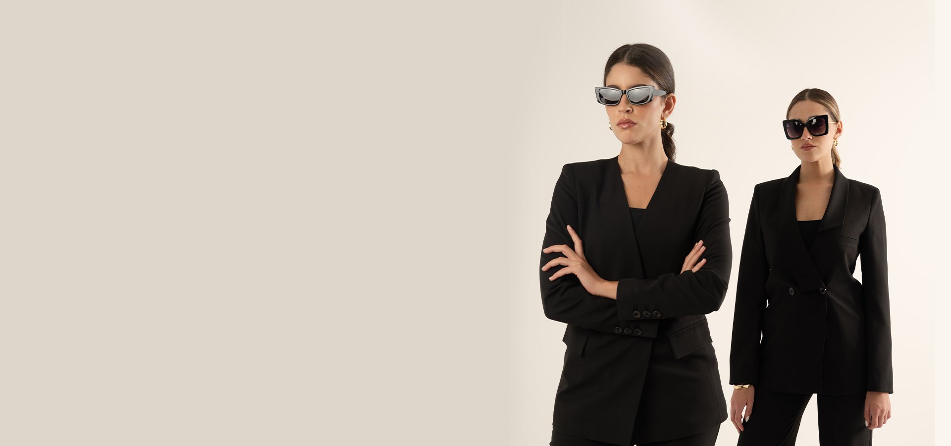 Two models in black tailored suits and sunglasses